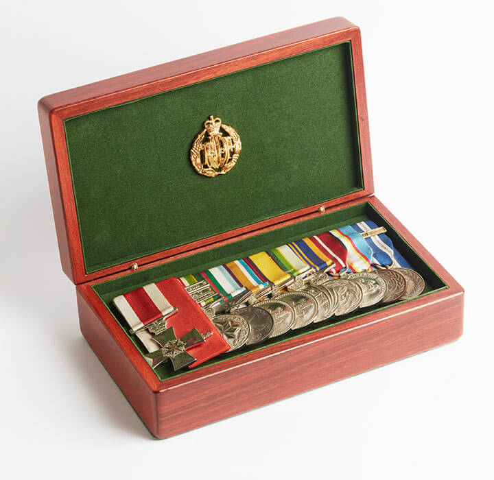 Large wooden medal box displaying array of military mdeals.