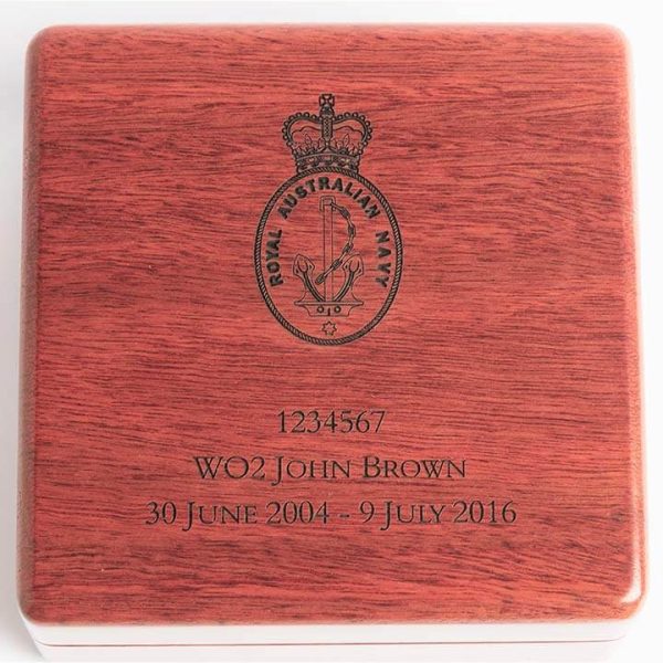 Close up of wooden lid on small medal box, showing personalised military engraving.